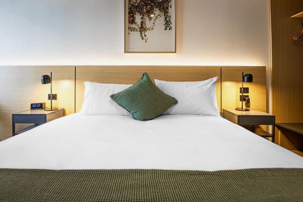Standard room with minimalist Scandinavian decor, queen bed, and natural oak finishes